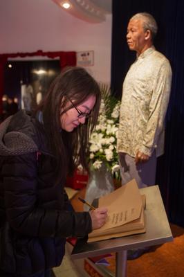游客在上海杜莎夫人蠟像館曼德拉蠟像邊的吊唁本上寫下唁詞，寄托哀思